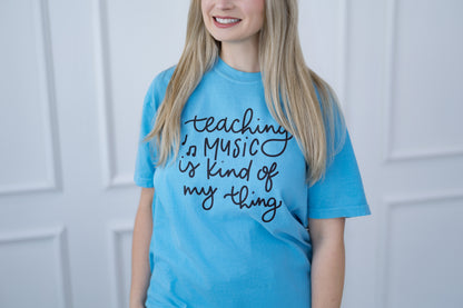 Person wearing a blue t-shirt with text, standing against a white paneled wall.