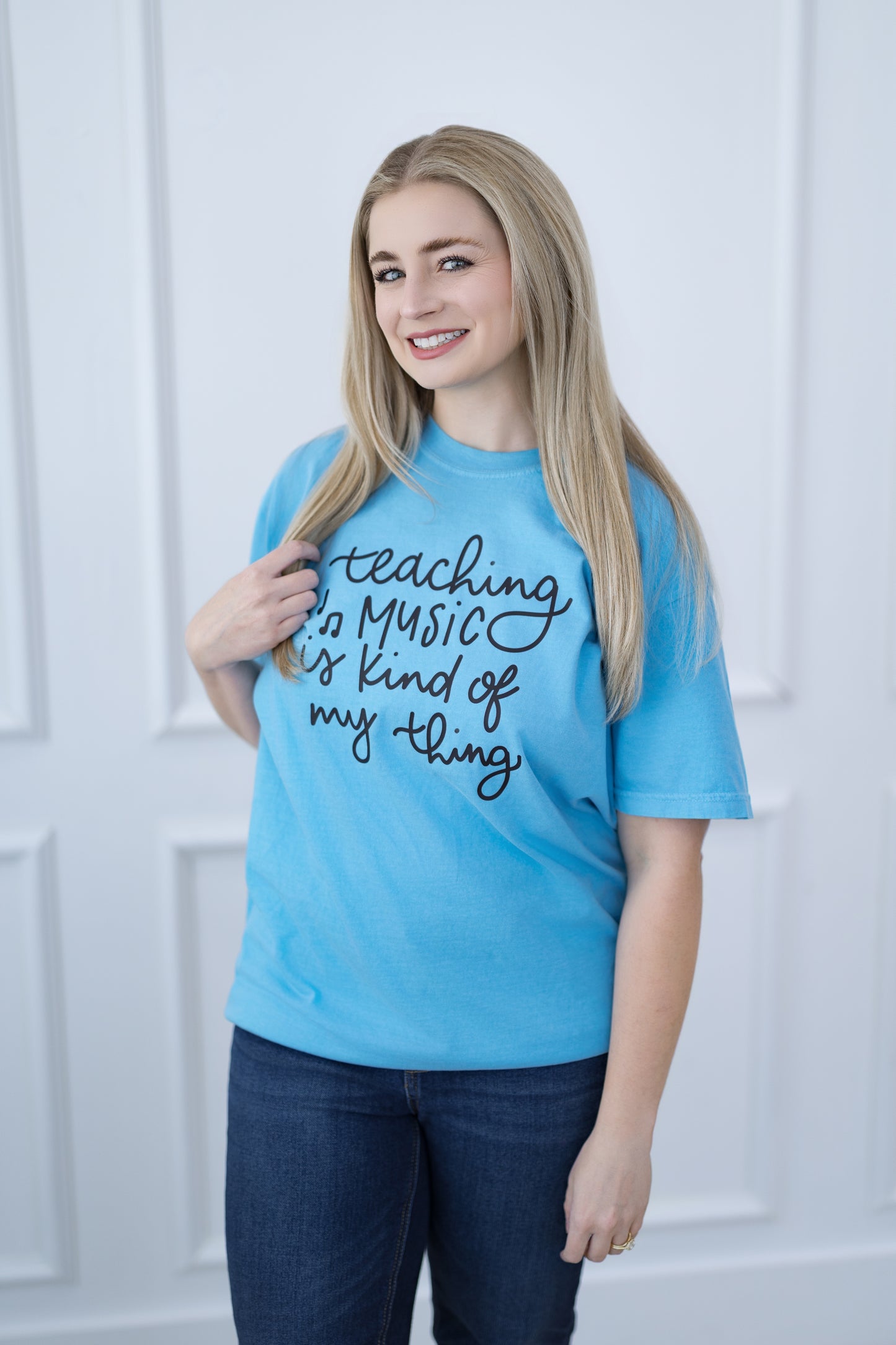 Person wearing a blue t-shirt with text, standing against a white background
