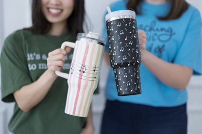 Two people holding insulated travel mugs with music-themed designs.