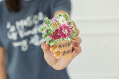 Hand holding a decorative claw clip with floral design against a blurred background 