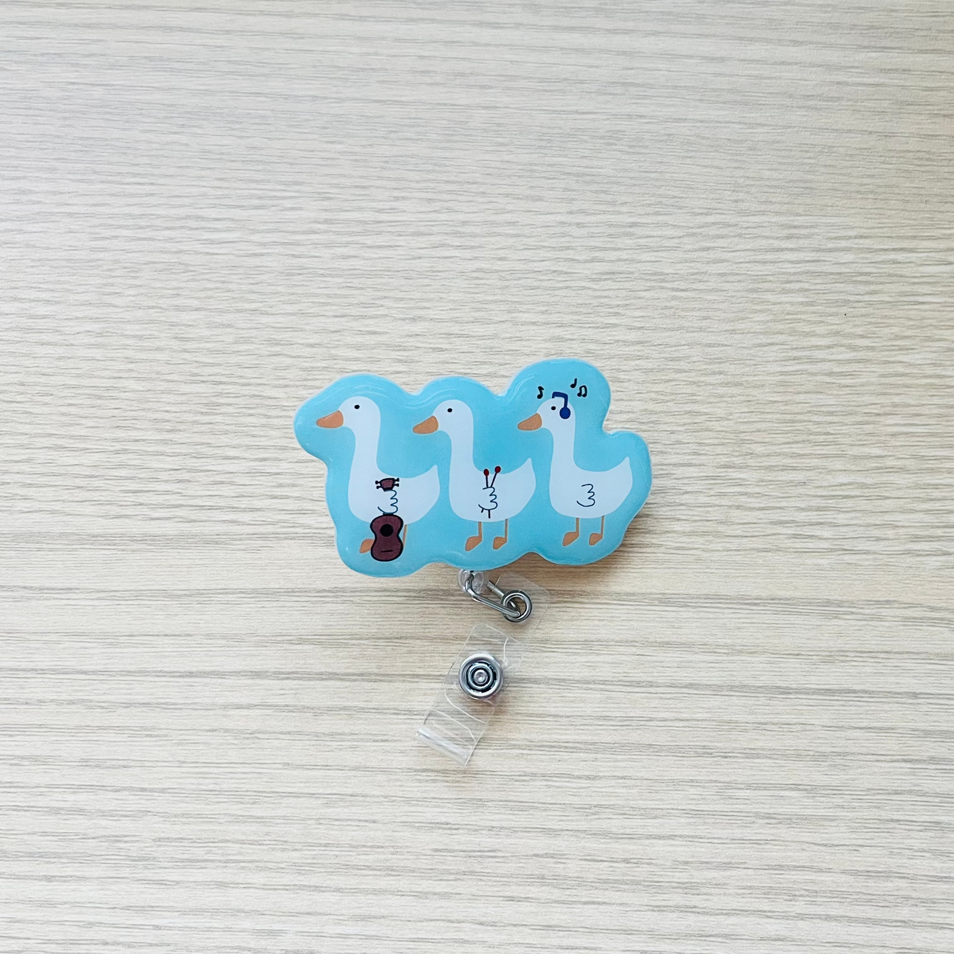 Retractable badge holder with cartoon ducks on a textured surface