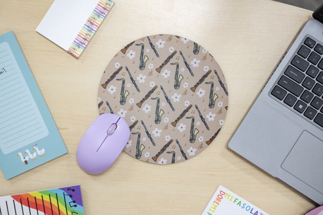 Round mouse pad with saxophone pattern on a desk with a laptop and mouse.