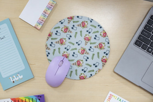 Floral mouse pad with a mouse on a desk next to a laptop and stationery items.