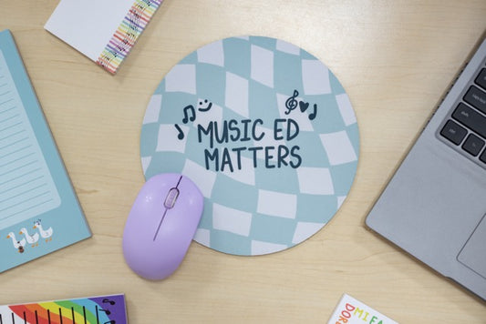 Round mouse pad with 'Music Ed Matters' text on a desk with a mouse, laptop, and stationery items.