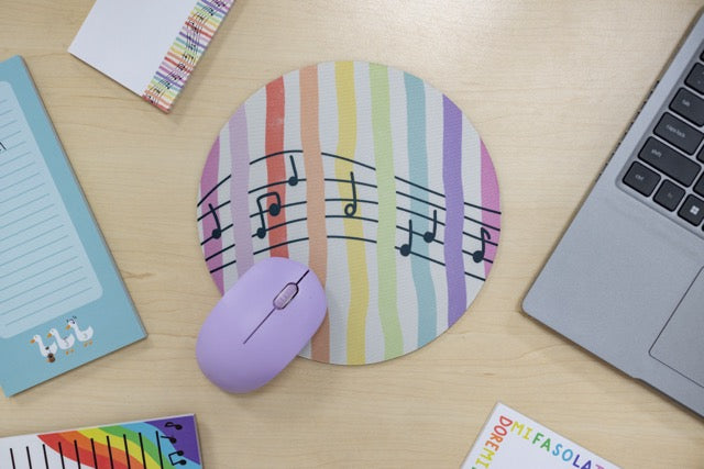 Colorful mouse pad with musical notes on a desk with a laptop and mouse.