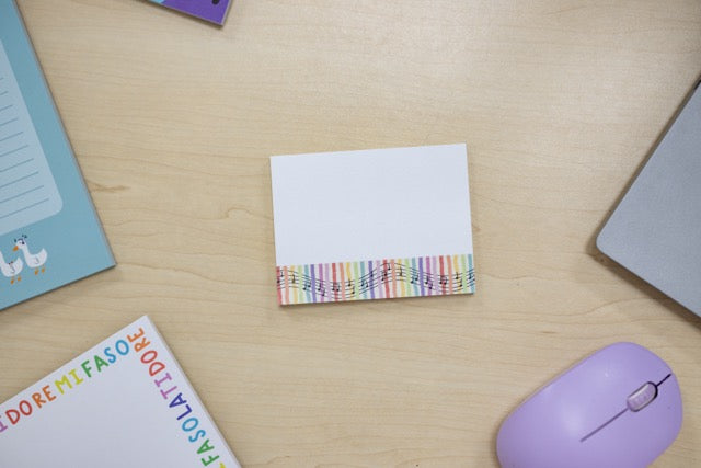 Colorful striped sticky notes on a wooden desk with a mouse and books.