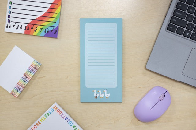 Note pads with colorful designs on a desk with a laptop and mouse.